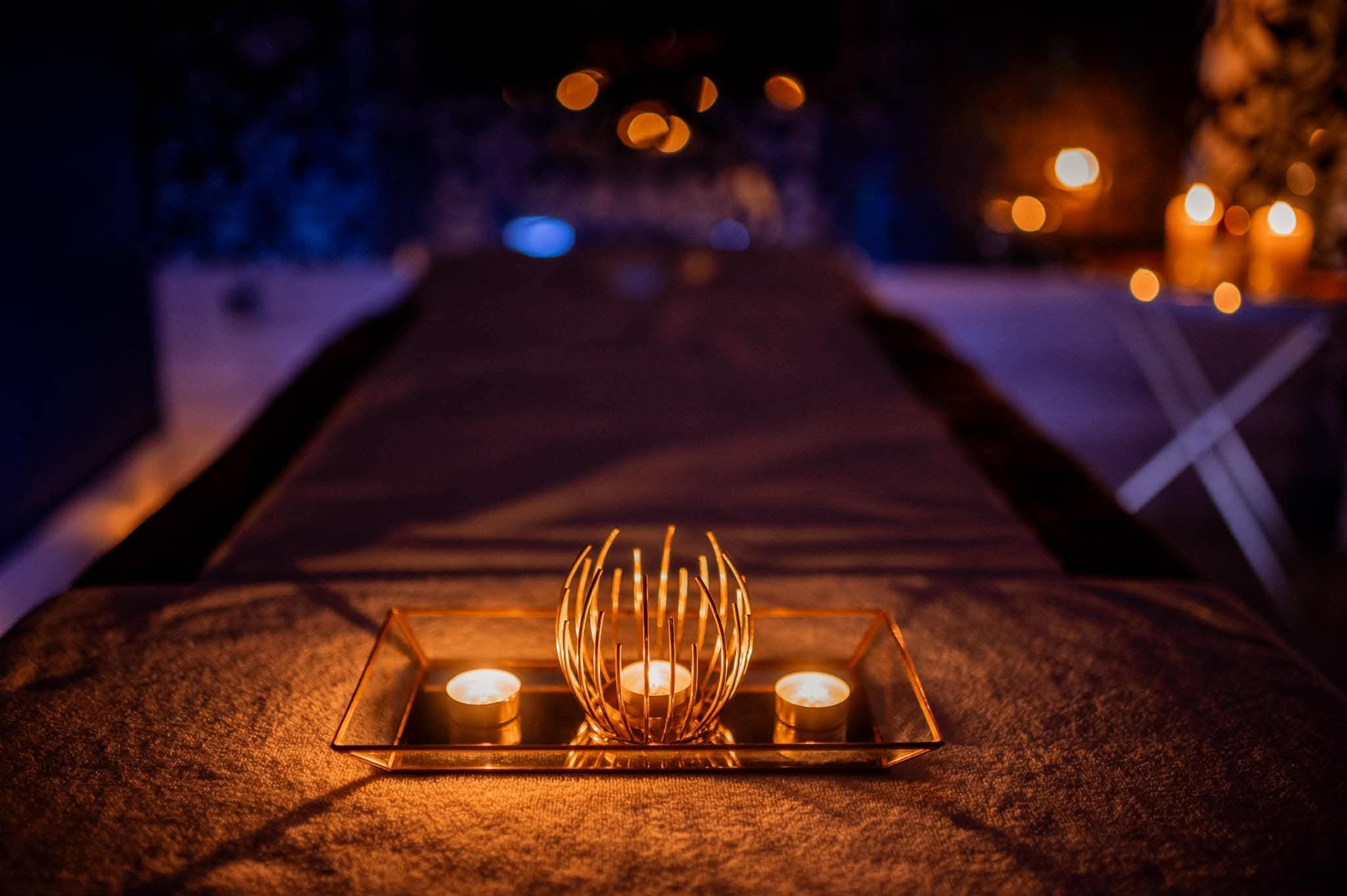 Ciepłe światło świec na leżance do masażu w gabinecie Namaste Massage Studio